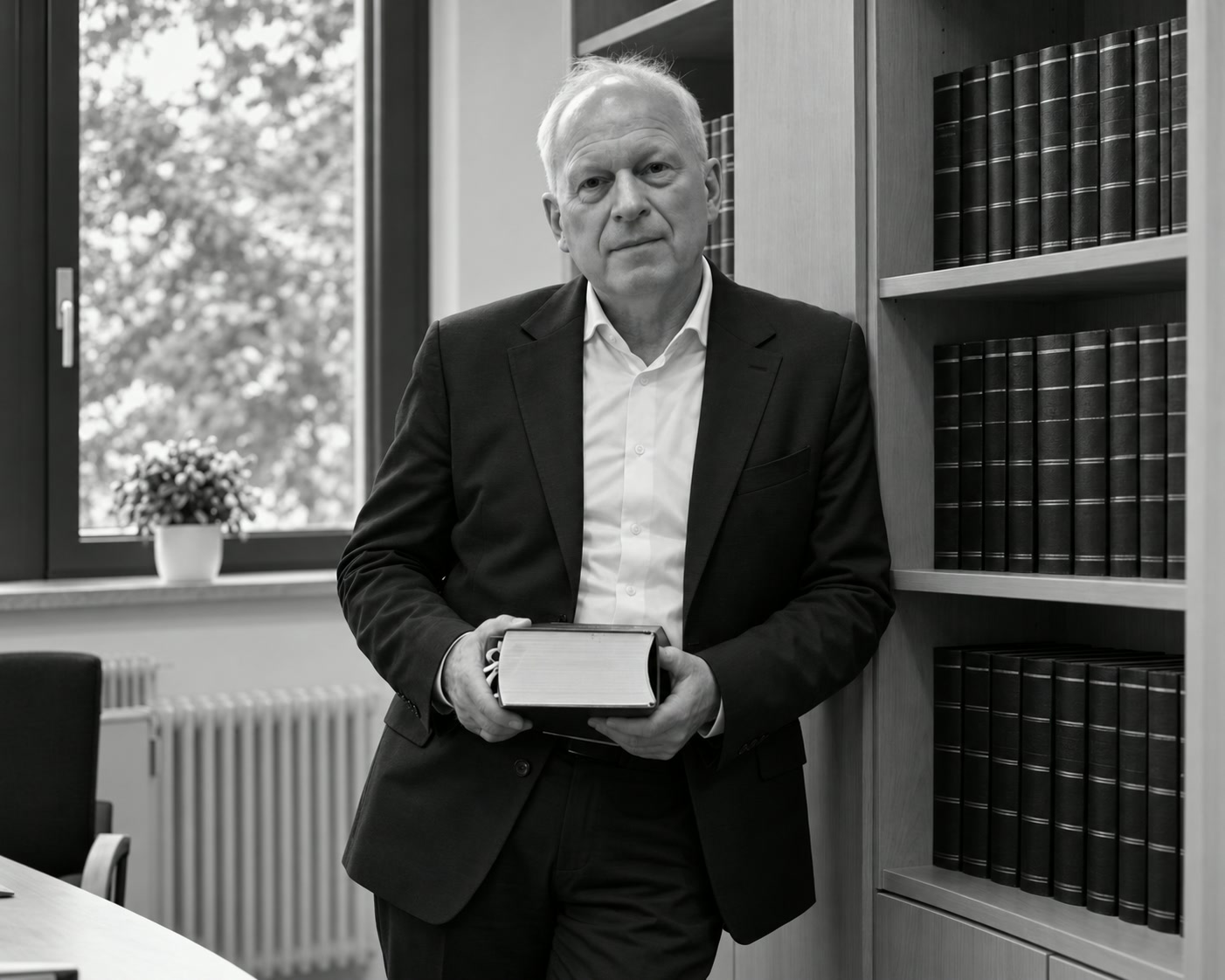 Rechtsanwalt Jürgen Röckel stehend an einem Bücherregal